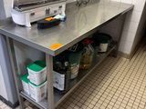 table de travail en acier inoxydable dans une cuisine professionnelle, sur laquelle sont posés des seaux contenant des produits d'entretien