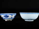 two blue and white bowls with designs on them on a black surface