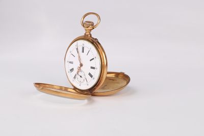 a gold pocket watch sitting on a white surface