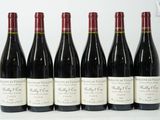 six bouteilles de vin sont alignées sur une surface blanche