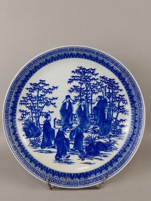 a blue and white plate with a painting of people on it