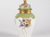 a close up of a green and white vase with flowers on it