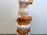 une statue représentant une femme assise sur un pot