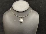 a silver necklace with a heart charm on a mannequin neck