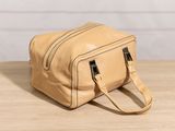 the small tan leather bag is sitting on a wooden table