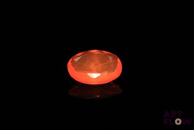 a close up of an orange diamond on a black surface