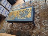 a coffee table with a painting on it in the middle of a living room