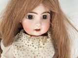 a close up of a doll with long brown hair