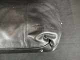 leather handbag on a black surface with a zippered closure