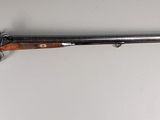 Un vieux fusil est accroché au mur d'une pièce.