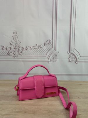 a pink purse on a wooden table with a white wall in the background
