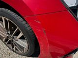 a close up of a red car that has a dent in it