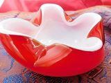a red bowl with a white flower in it on a table