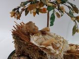 a figurine of a baby in a basket under a tree