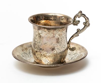 an antique silver cup and saucer on a saucer