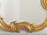 a mirror with a gold frame on a white surface