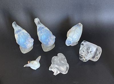cinq oiseaux en verre posés sur une surface noire