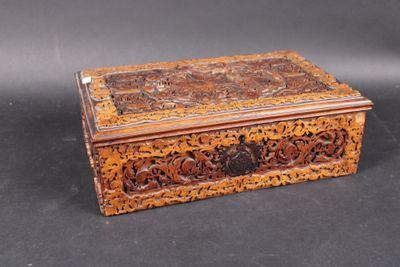 an old wooden box with carvings on it sitting on a black surface