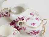 three cups and saucers on a table with a teapot