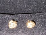 deux paires de boucles d'oreilles à clous dorées posées sur un tissu noir