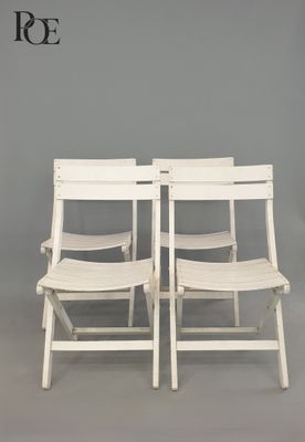 pair of white folding chairs against a gray wall