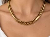 une femme portant un collier à chaîne en or et des boucles d'oreilles