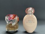 two bottles of perfume sitting next to each other on a table