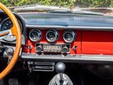 dashboard of a red car with a wooden steering wheel and gauges
