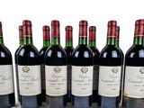 six bottles of red wine lined up in a row on a white surface