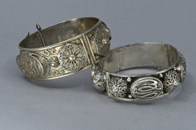 pair of silver bracelets with engraved designs on them on a gray surface