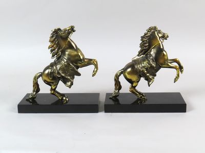 une paire de serre-livres anciens en laiton représentant des chevaux, posés sur des socles en marbre noir
