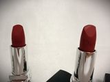 two red lipsticks sitting on top of each other on a white surface