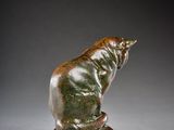 bronze sculpture of a cat sitting on a rock on a gray background