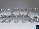 six verres à vin en cristal sont alignés sur une surface blanche