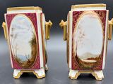 two vases with paintings on them sitting on top of a table