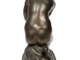 bronze statue of a woman sitting on a pedestal with her back to the camera