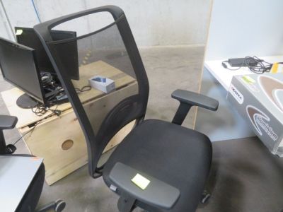 une chaise de bureau noire sur laquelle est posé un écran d'ordinateur