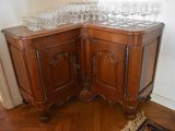a corner cabinet with wine glasses on top of it
