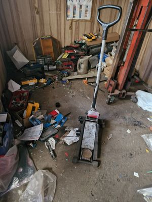 a pile of junk in a garage with a shovel and other tools