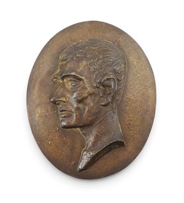 un médaillon ancien en bronze représentant le visage d'un homme sur fond blanc