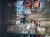 une étagère en verre sur laquelle sont posés des verres à vin et une horloge