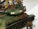 a toy army tank with a man standing next to it