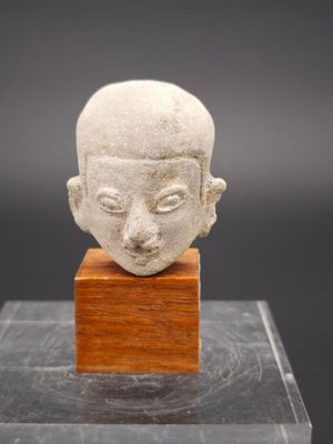 un gros plan d'une sculpture représentant une tête posée sur un socle en bois