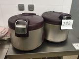 two rice cookers sitting on a table in a kitchen
