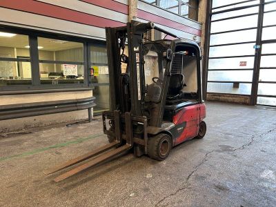 un chariot élévateur au milieu d'un parking, devant un immeuble