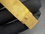 a close up of a person ' s hand holding a gold tie bar