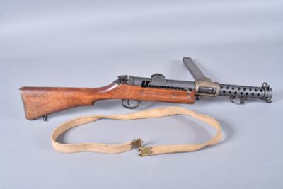 an old machine gun with a sling on a white surface