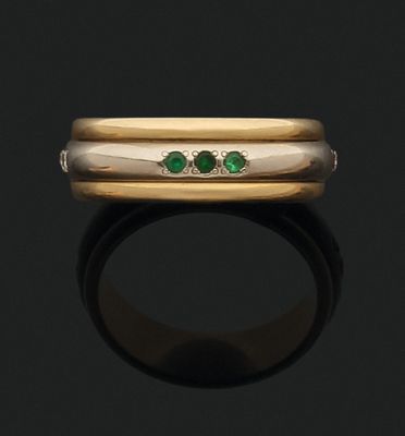 un gros plan d'une bague en or sertie de deux émeraudes