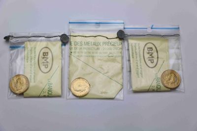 trois sachets de pièces d'or et une pièce de dix cents posés sur une surface blanche