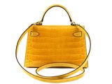 the small yellow handbag is sitting on a white surface